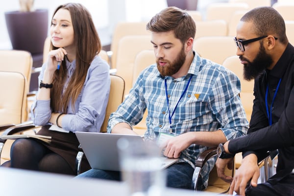 Multiethnic group of young business people using laptop sitting on meeting in conference hall