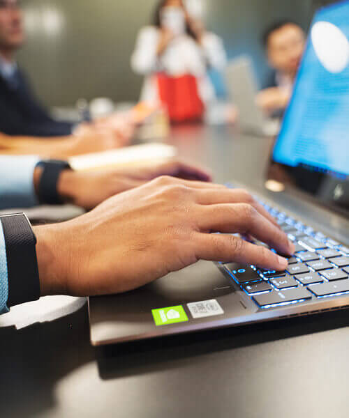 An enSYNC team member types on a laptop.