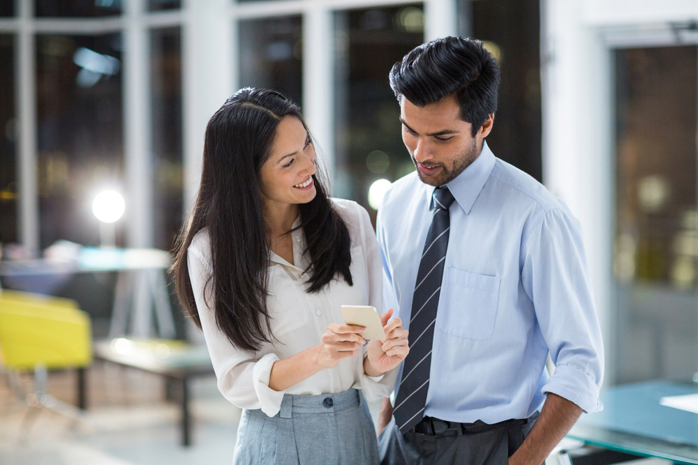 Businesswoman showing mobile phone to colleague in the office-1