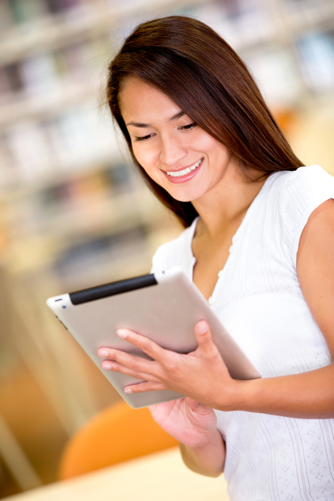 Woman with tablet computer reading a book Woman with tablet computer reading a book