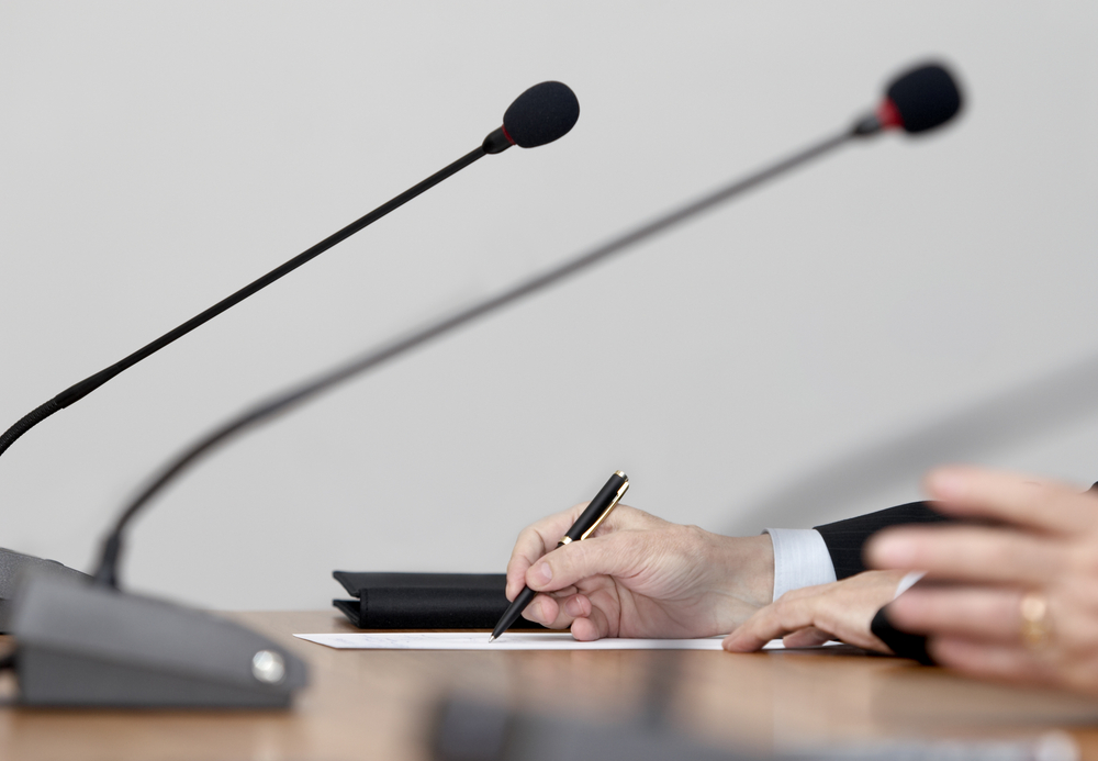 close up of conference meeting microphones and businessman writing